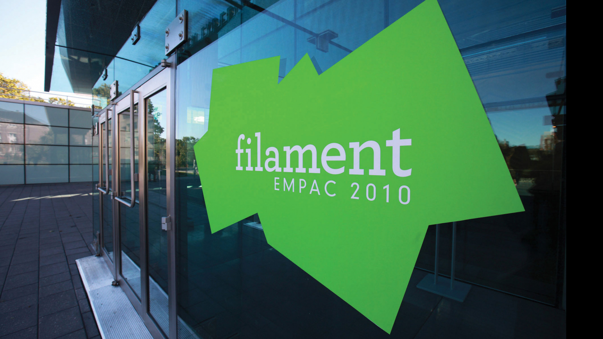Lime green jagged shape on the exterior glass of EMPAC reading in white font, "filament, EMPAC 2010". 