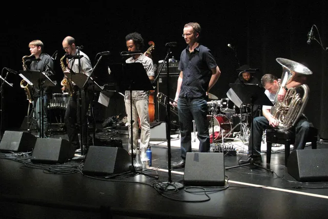 A small group of musicians playing a concert on a black stage. 