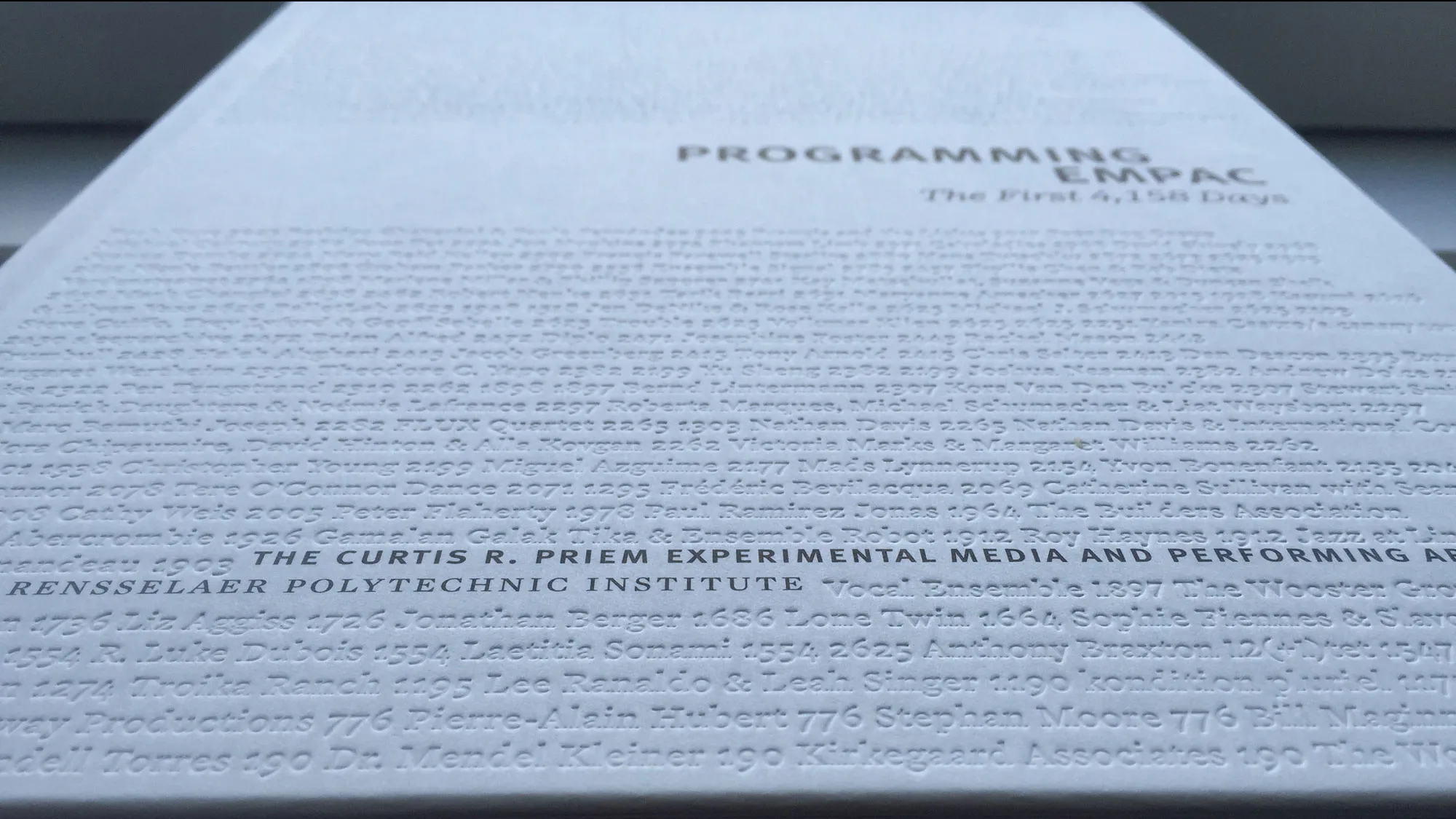 Textured cover of a white coffee table, black text reads Programming Empac. 