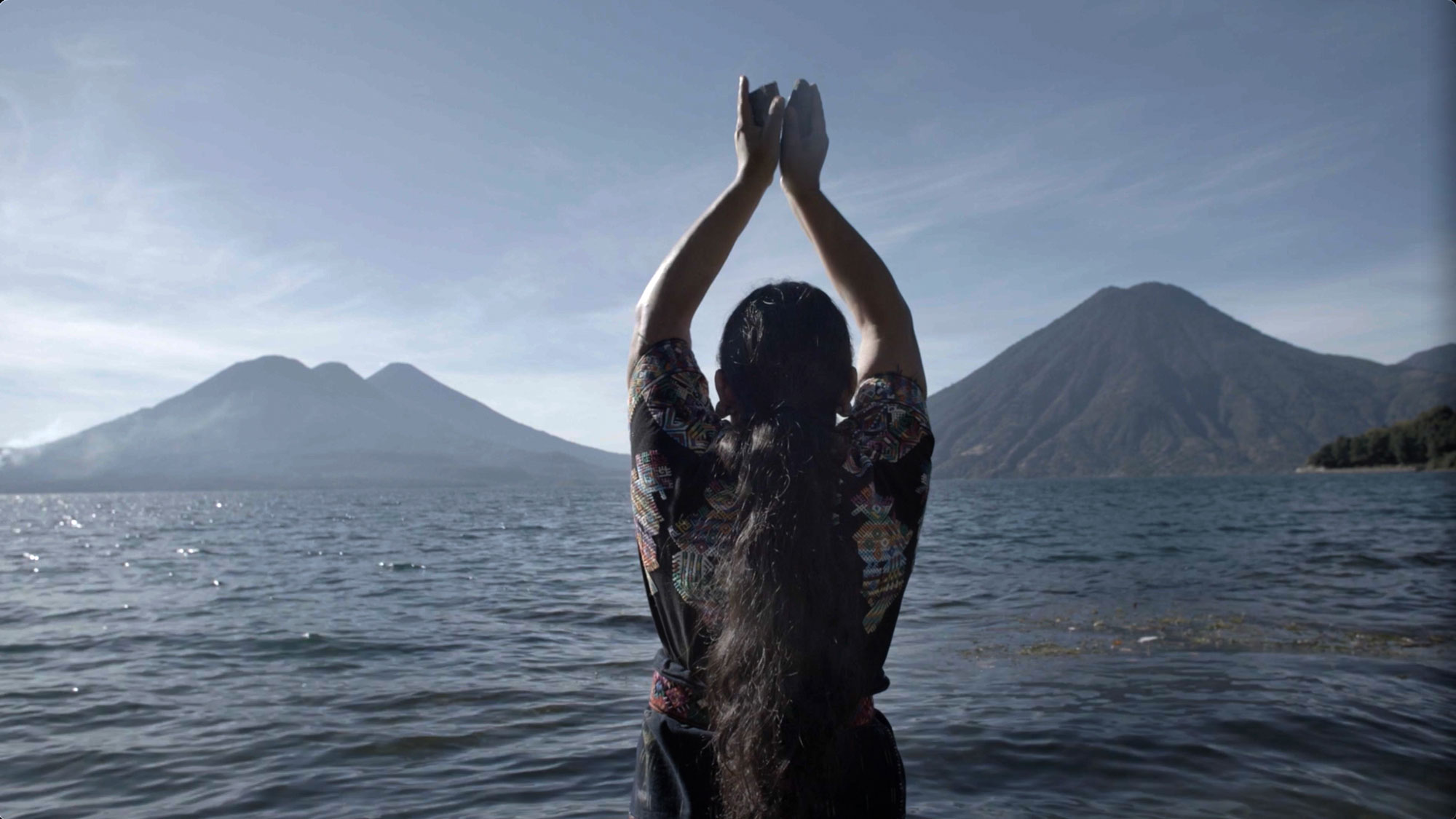 a woman hands held high with offering worships a volcano