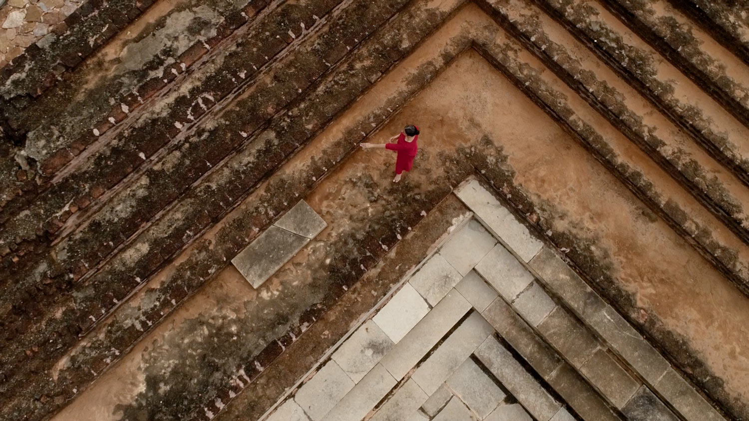a woman walking up a earthen step pyramid
