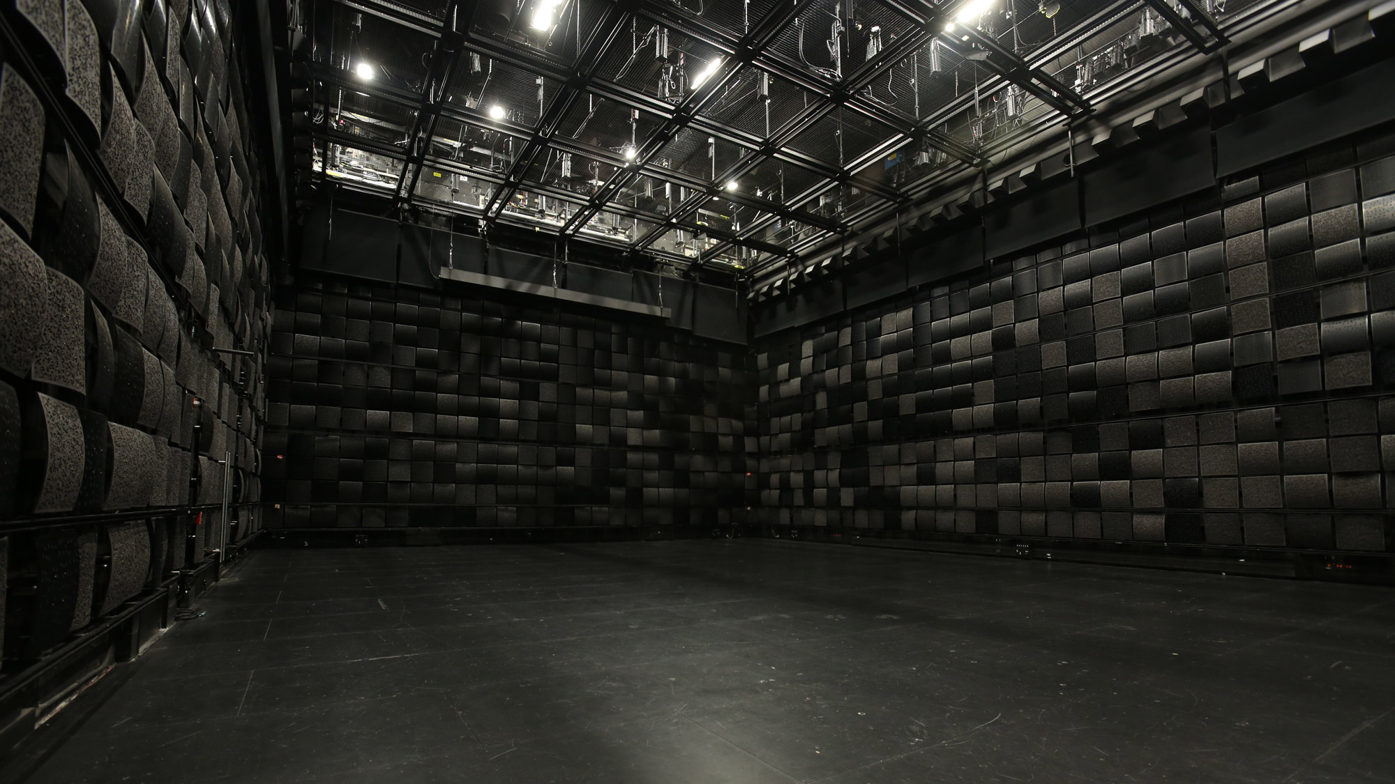 a black studio box with black acoustic tiles and a grid