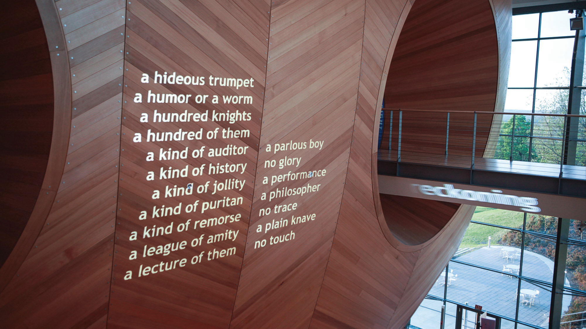 White text projected on to the wood hull of the concert hall that read "a hideous trumpet, a humor or a worm, a hundred of them, a kind of auditor, a kind of history, a kind of jollity, a kind of Puritan, a kind of remorse, a league of amity, a lecture of them, a parlous boy, no glory, a performance, a philosopher, no trace, a plain knave, no touch" 