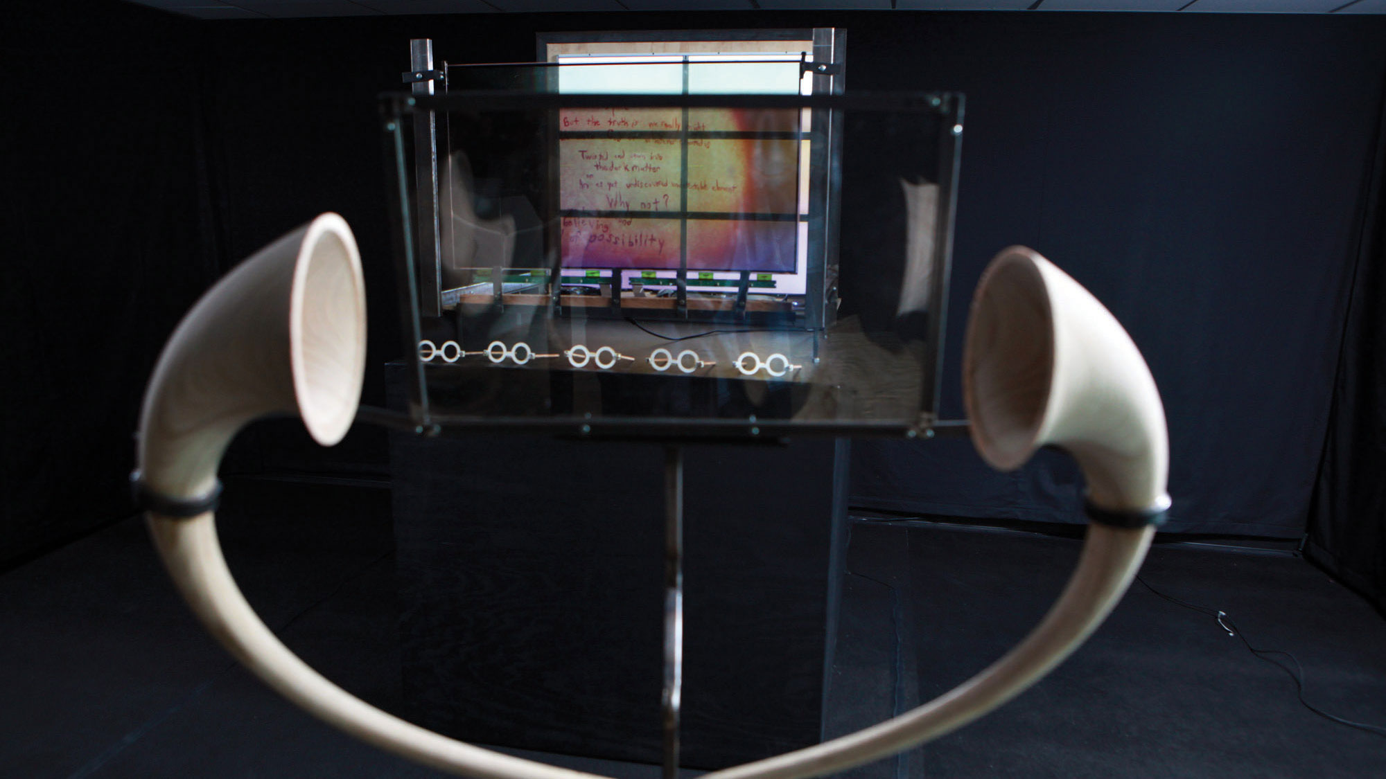 Two white listening horns in front of and framing a piece of polarized glass. 