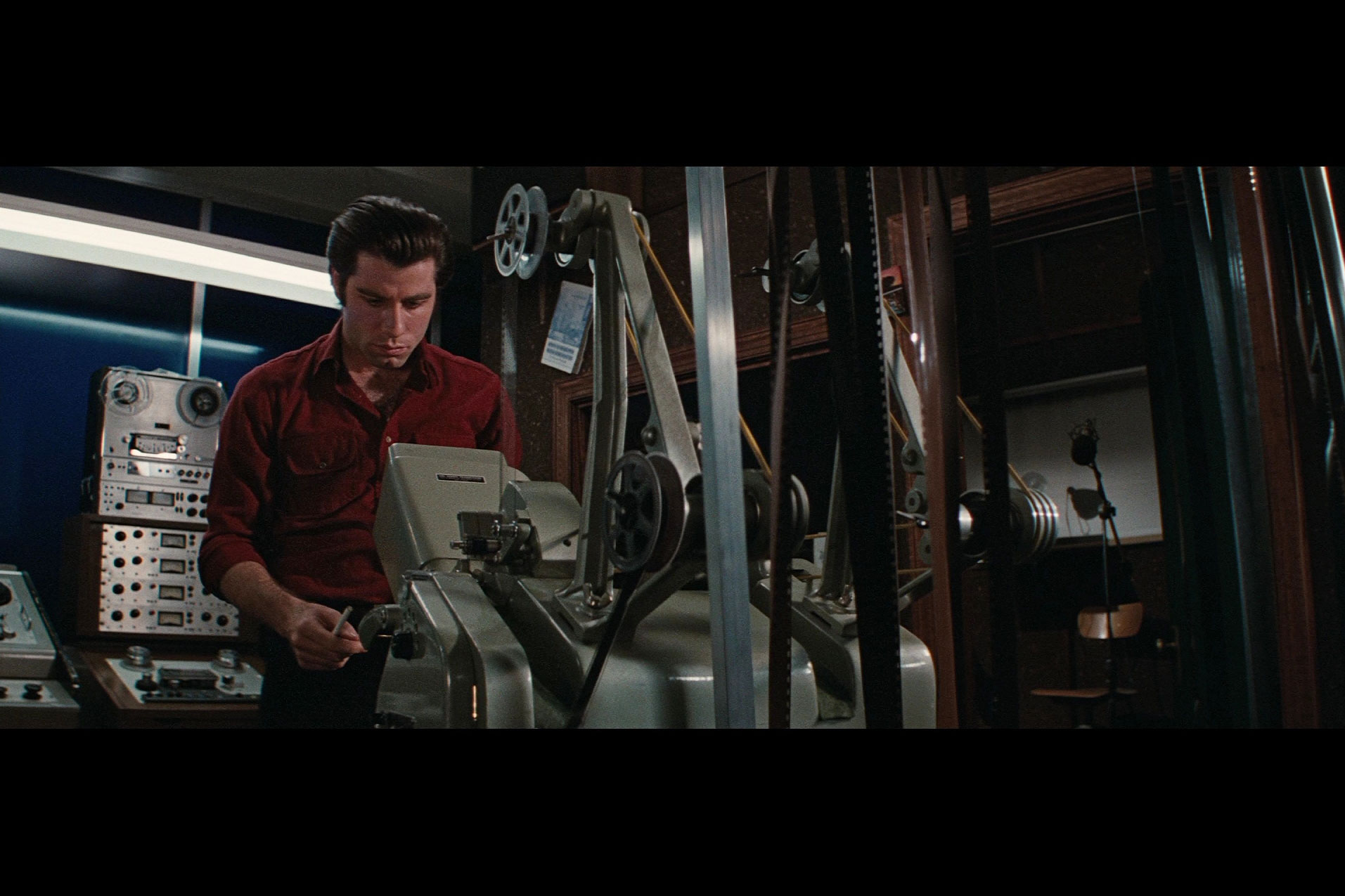 john travolta standing behind a projector in a projection booth. 