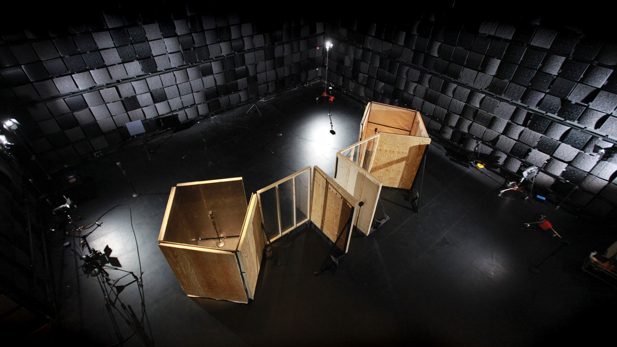 An aerial view of two square wooden structures in an empty black box studio. 