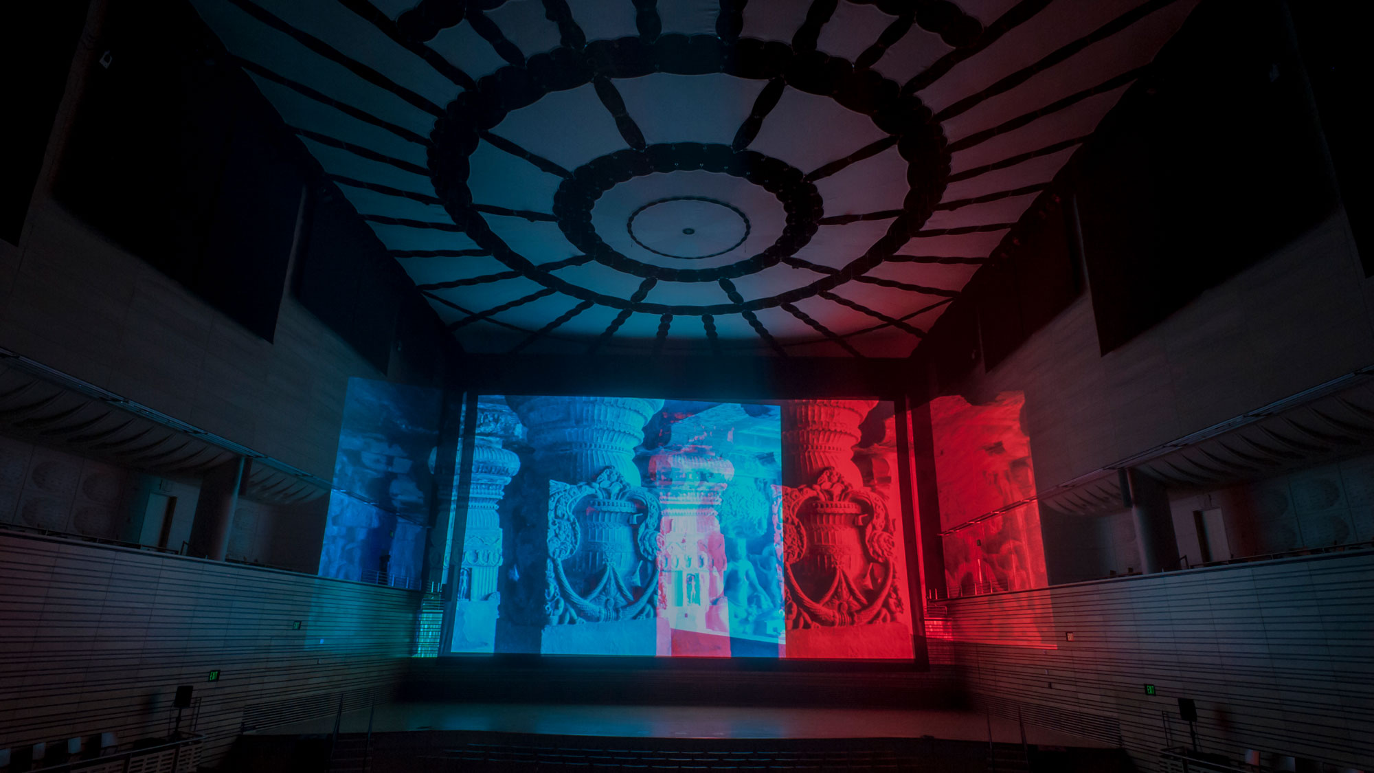 A projection of ornate classical/corinthian style columns in blue and red on the concert hall back wall. 