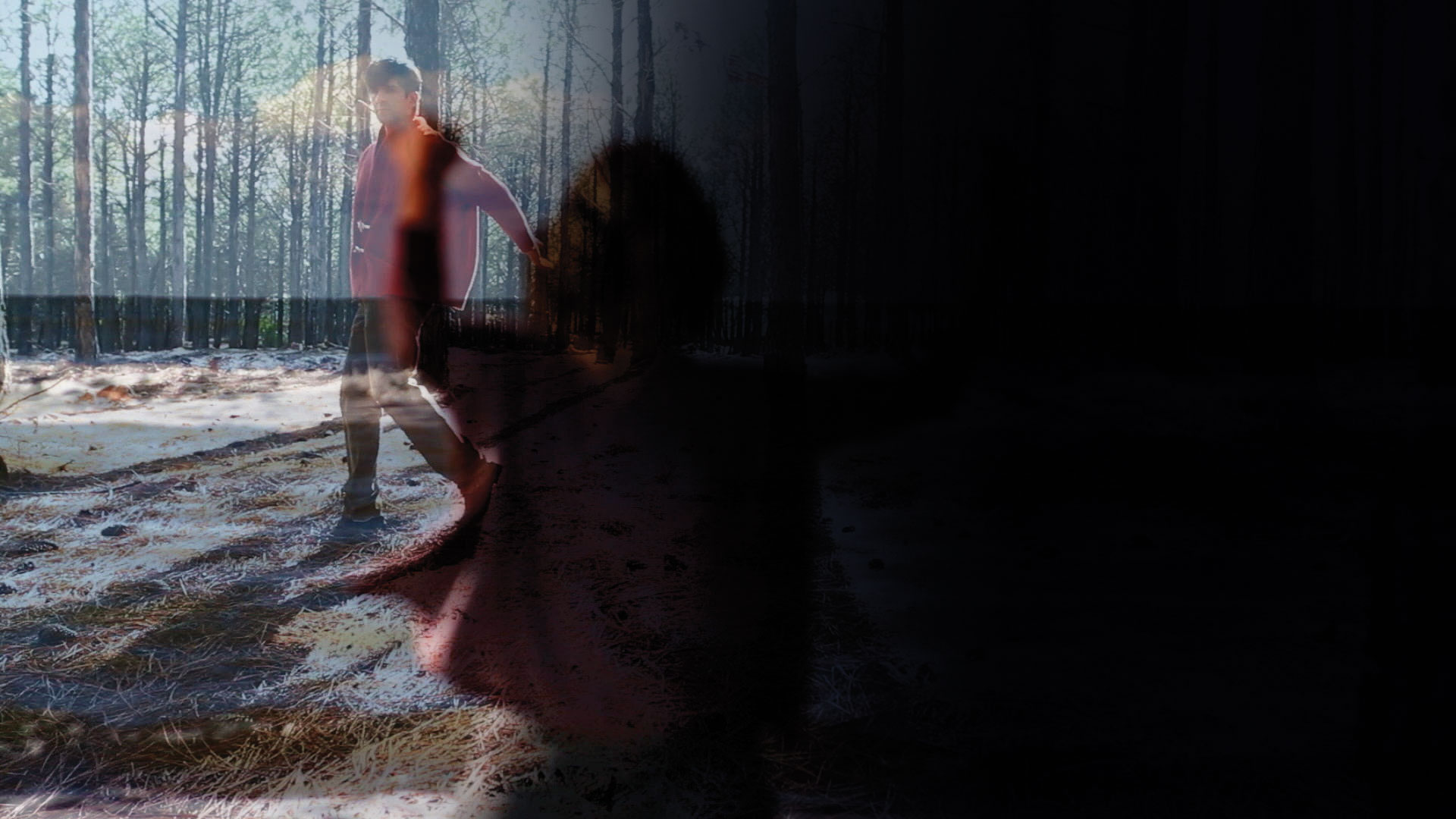 A double exposed image of a shadow of a woman reaching and a man wearing a red jacket walking through a sun dappled forest. 