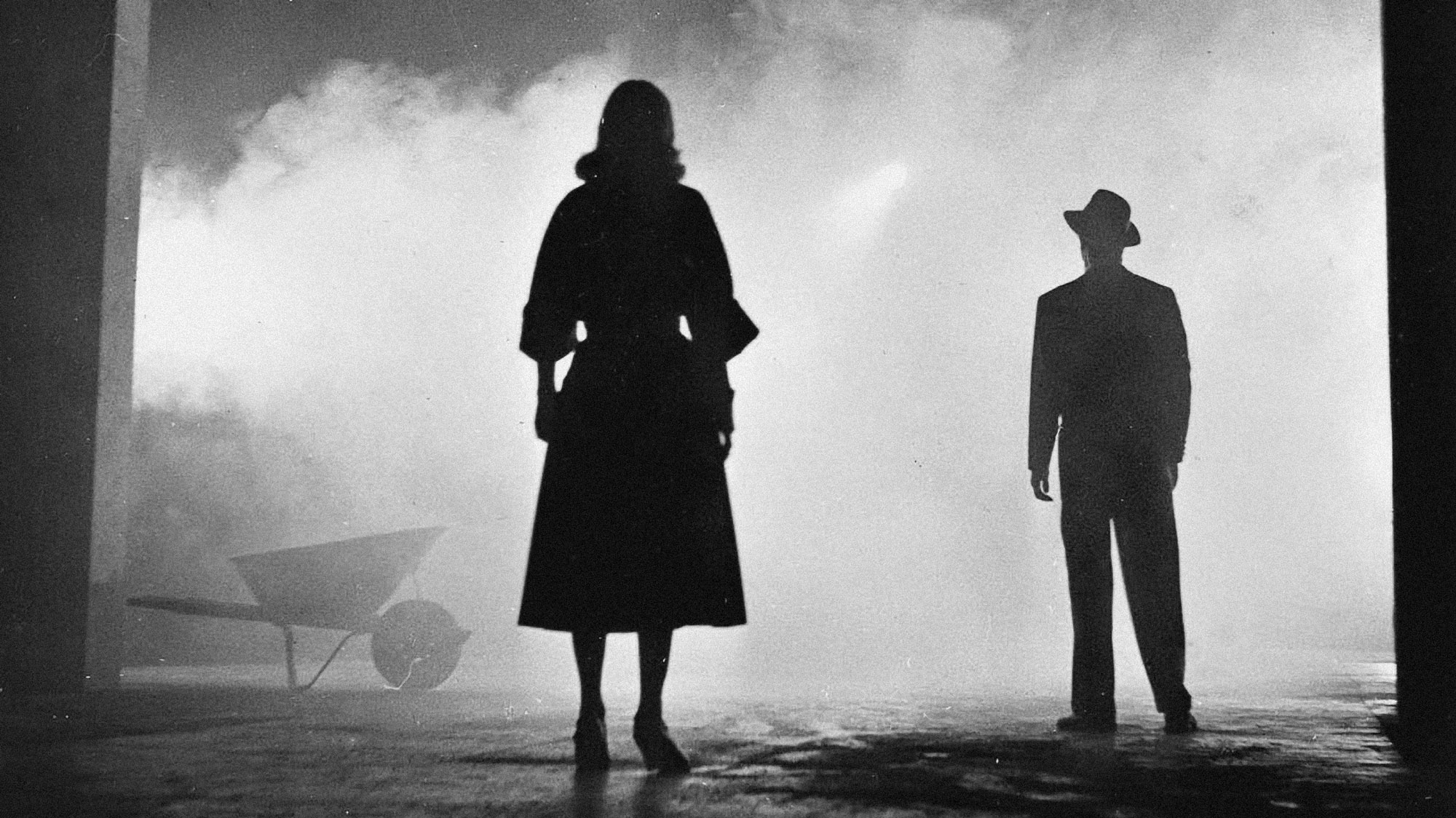 1940's scene of a man and woman with backs to the viewer silhouetted in fog. 