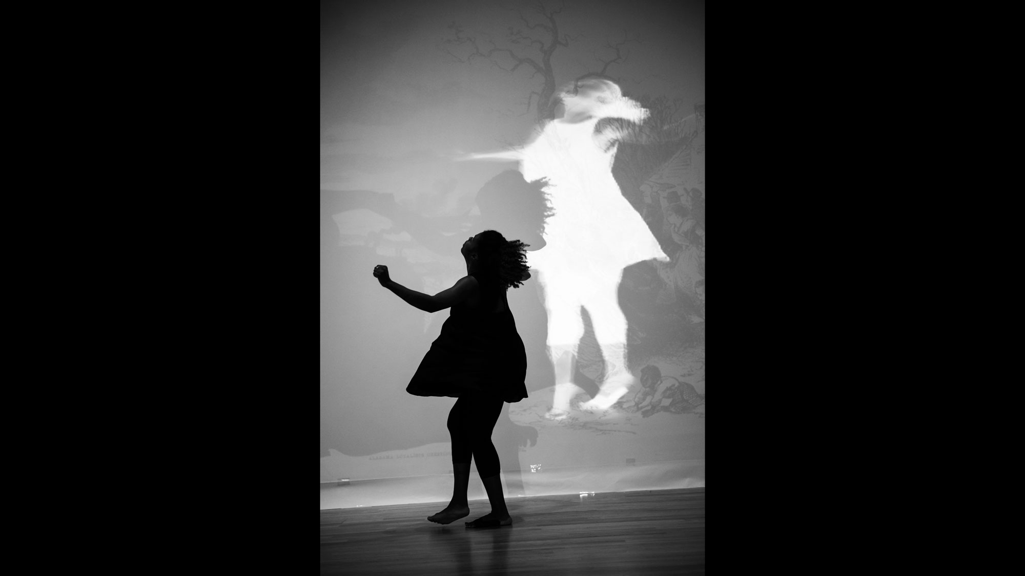 An inverse shadow of a young Black girl twirling with arms outstretched in a dress. 