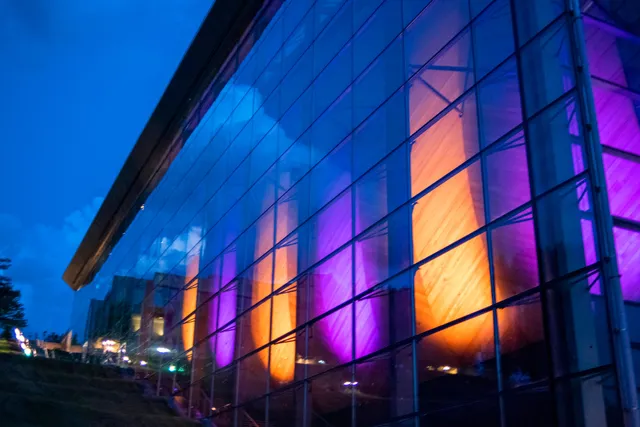 The EMPAC exterior lit from within with purple and gold at night. 