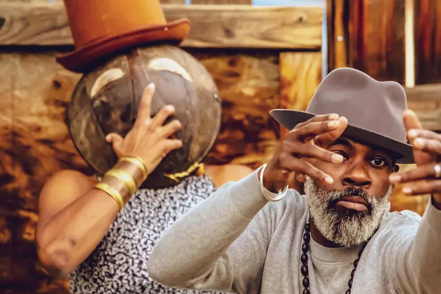 a black man with a grey beard reaching out toward the camera.