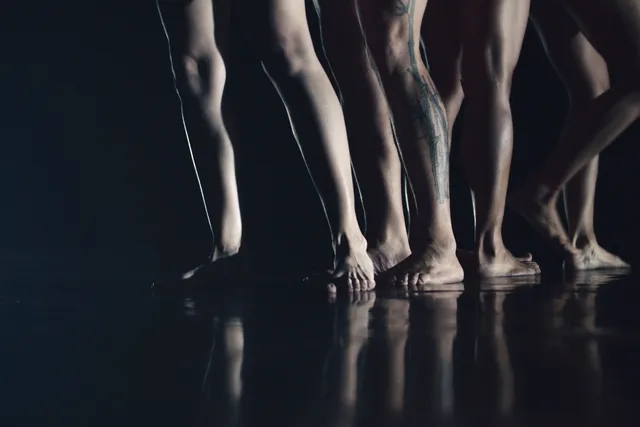 four pairs of legs on a black stage.