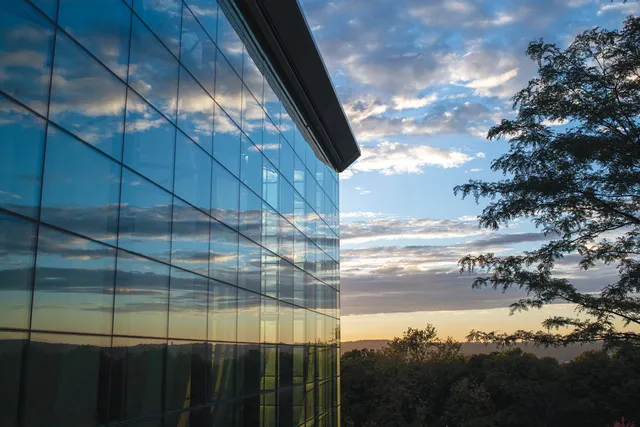 clouds in the evening sky reflecting off empacs glass curtain wall on its north facade