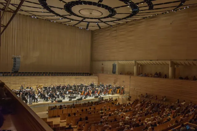 a full orchestra on stage in EMPAC's Concert hall with a large audience in attendance