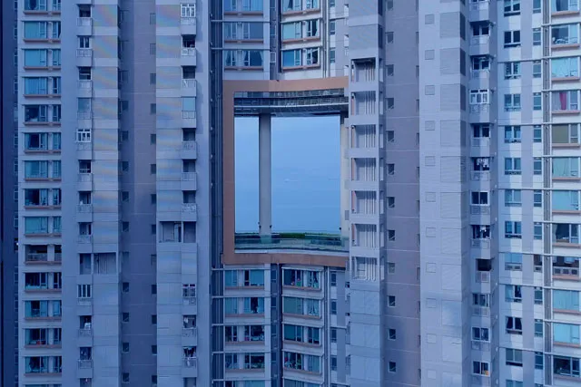 A high-rise apartment building with a large window or opening in the middle. 