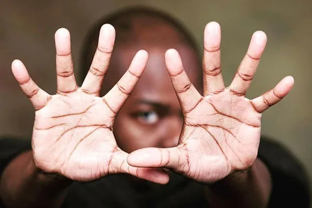 Jaamil Olawale Kosoko with hands out reached to the camera framing his eye.