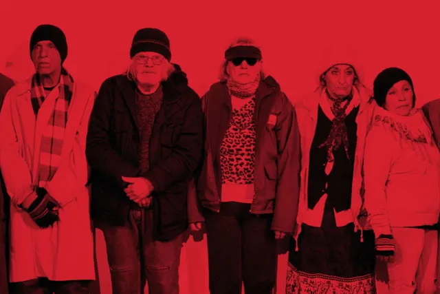 a group of five people bundled in layers of winter clothes washed in red light. 