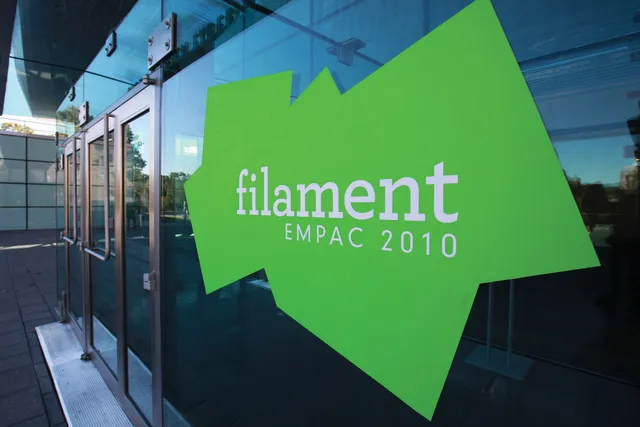 Lime green jagged shape on the exterior glass of EMPAC reading in white font, "filament, EMPAC 2010". 