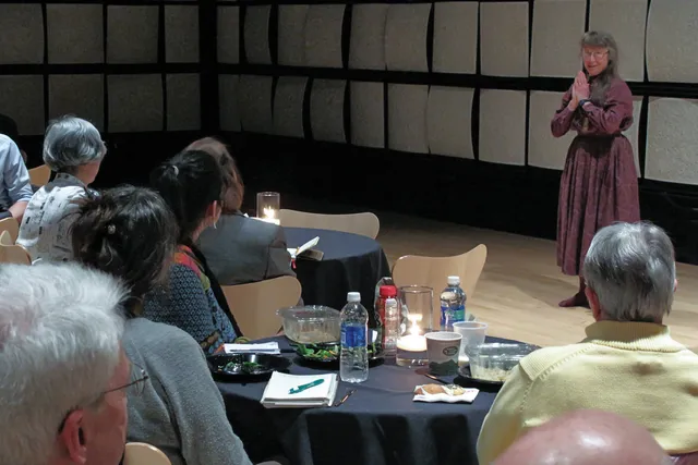 Maxine Sheets-Johnstone addressing people seated on round tables.