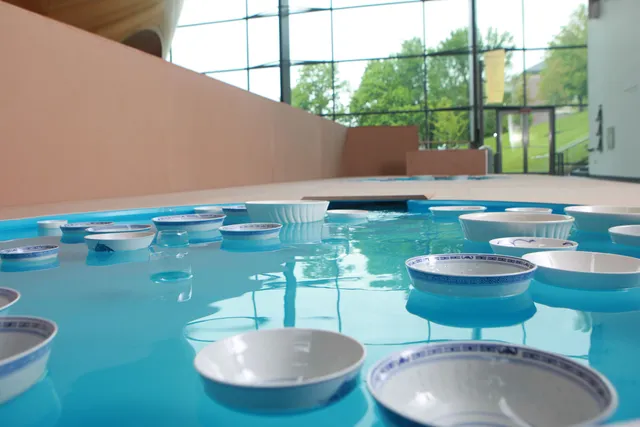 Numerous blue and white porcelain bowls floating in a blue pool on the mezzanine the interior of EMPAC. 