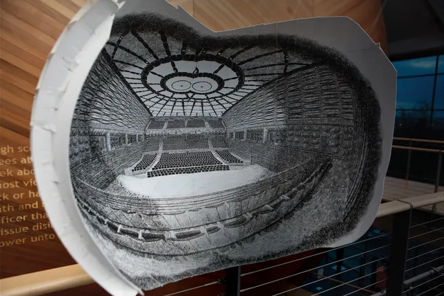 A black and white sketch model of the concert hall set in front of the completed concert hall.