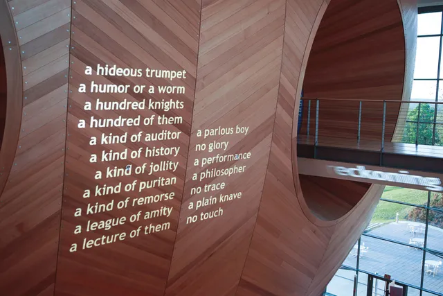 White text projected on to the wood hull of the concert hall that read "a hideous trumpet, a humor or a worm, a hundred of them, a kind of auditor, a kind of history, a kind of jollity, a kind of Puritan, a kind of remorse, a league of amity, a lecture of them, a parlous boy, no glory, a performance, a philosopher, no trace, a plain knave, no touch"