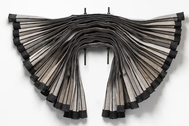 Gray canvas fabric shaped into wings and mounted on a white wall.