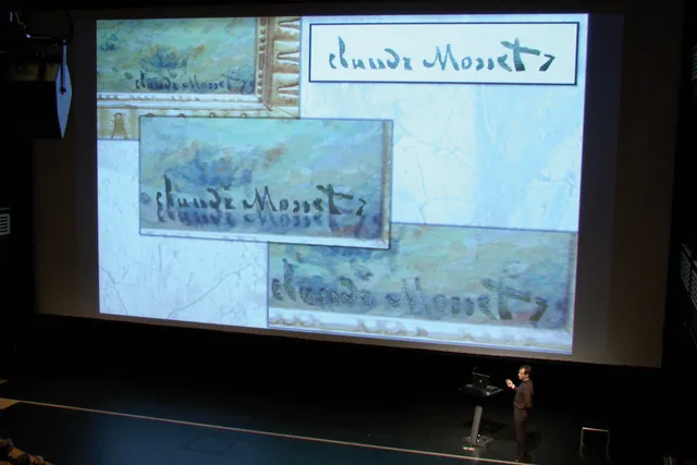A large screen projecting four images of Claude Monet's signature.