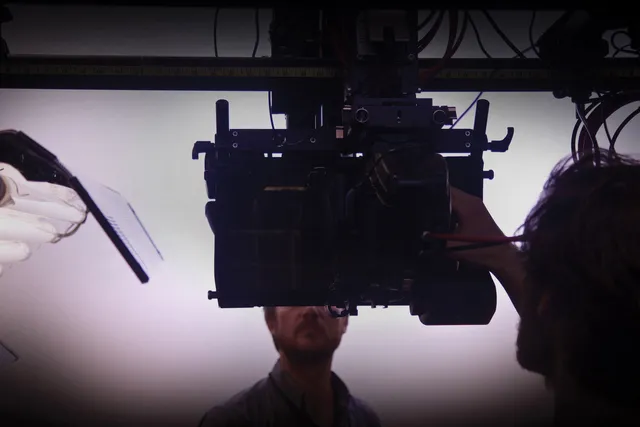 A white man looking directly into a video monitor.