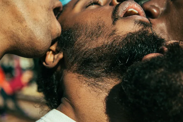 Four Black men in close proximity with mouths open creating a sexual scene. 