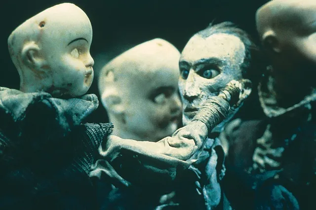 Green tinted distressed porcelain doll heads missing their hair and eyes.