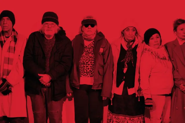 a group of six people bundled in layers of winter clothes washed in red light. 