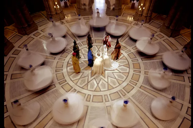 An aerial view of a whirling dervishes with a group of individuals wearing various regalia in the middle. 