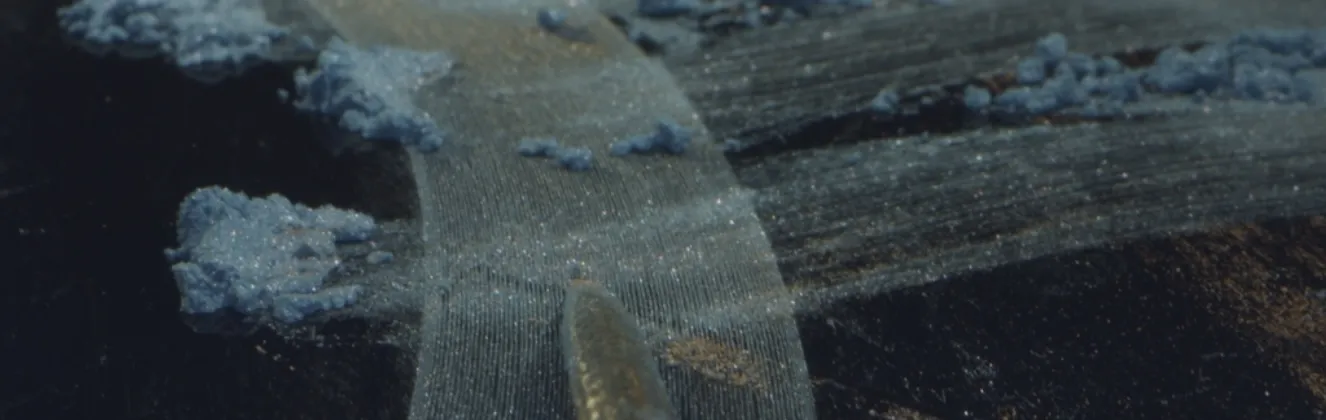 metallic blue dust scattered across grooved surface with stylus