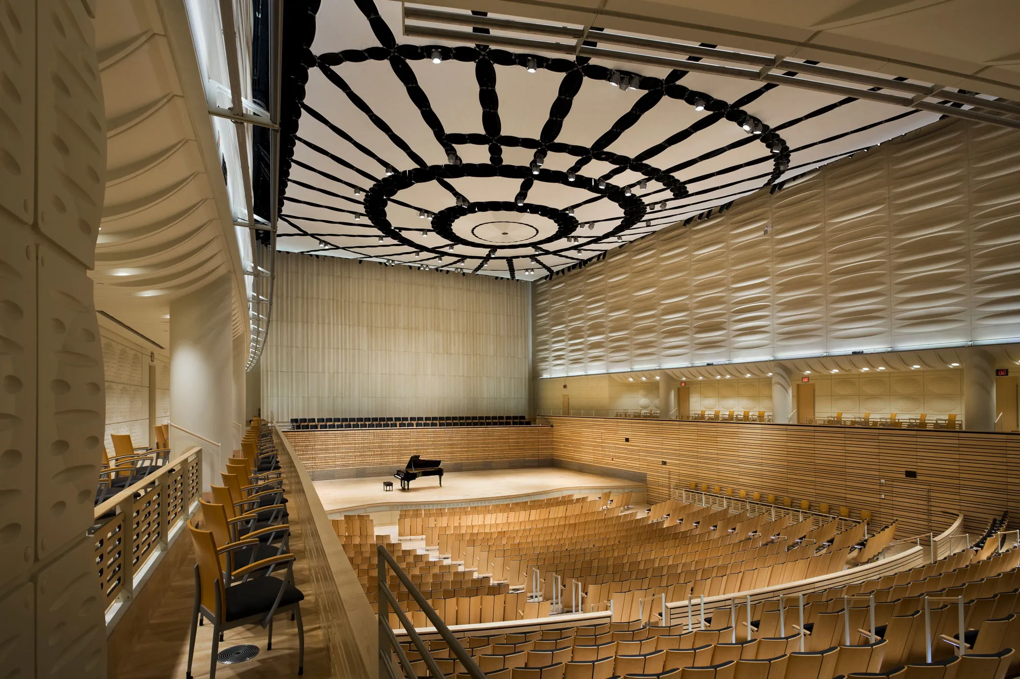 A single grand piano sitting on the empty concert hall stage.