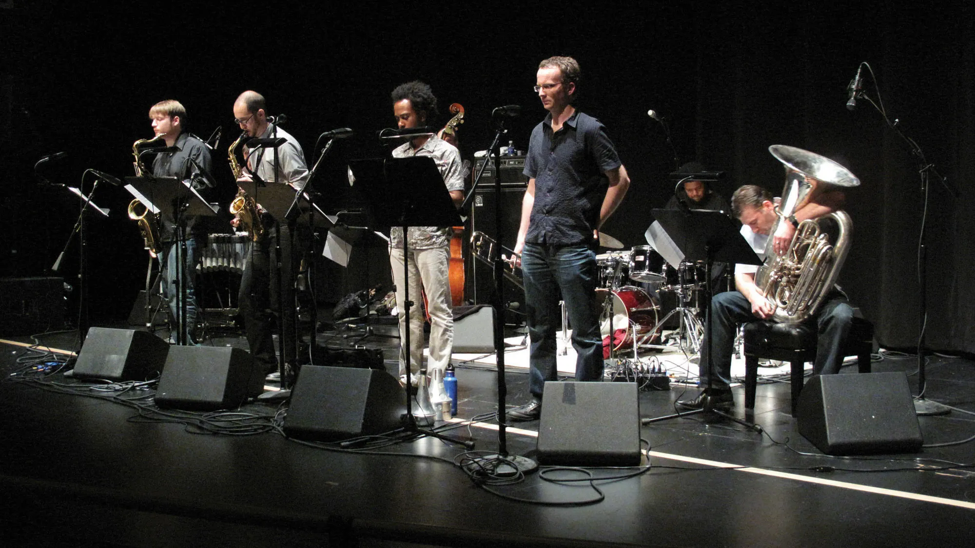 A small group of musicians playing a concert on a black stage.
