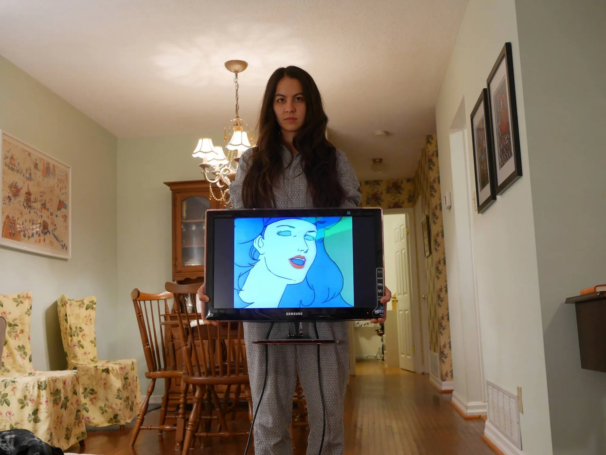 Alison Kobayashi standing in a traditionally styled dining room behind a screen showing a cartoon woman. 