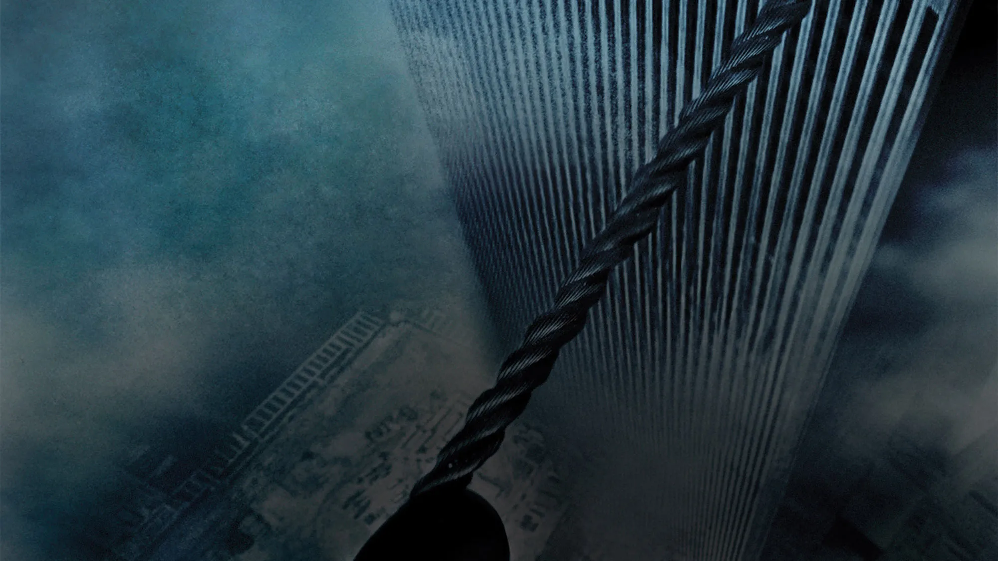 A point of view shot of looking down on a tight wire stretched between two high-rise buildings on a great, foggy day.