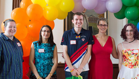 members of the lgbtq task force pictured with graduation students under rainbow balloons